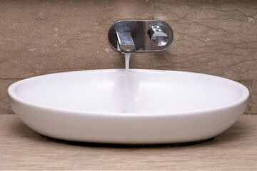 Front view of bathroom sink basin and open chrome faucet washbasin. Silver taps on brown granite...