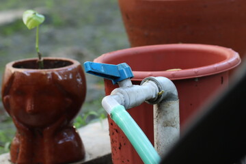 Water faucet and hose with flowerpot background