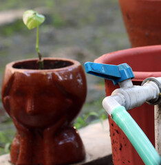 Water faucet and hose with flowerpot background
