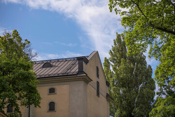 Façade, tin roof and dorms on a 1800s stone building a sunny summer day in Stockholm