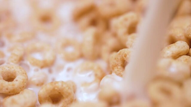 Slow motion pouring milk into a bowl of breakfast cereal bubbling as it mixes