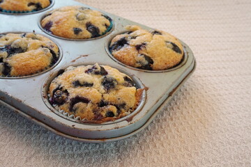Muffin Tin with Baked Blueberry Muffins on Textured Towel