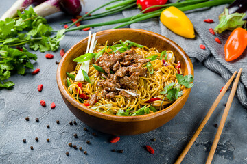 beef wok noodles with vegetables on wooden bowl, egg noodles