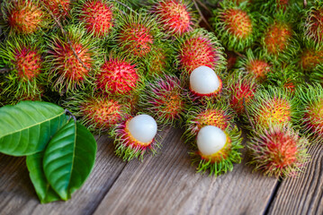 Obraz na płótnie Canvas Rambutan fruit on wooden background harvest from the garden rambutan tree, Fresh and ripe rambutan sweet tropical fruit peeled rambutan with leaf