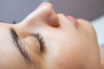 Close-up portrait of a young caucasian woman before eyelash lamination procedure. 