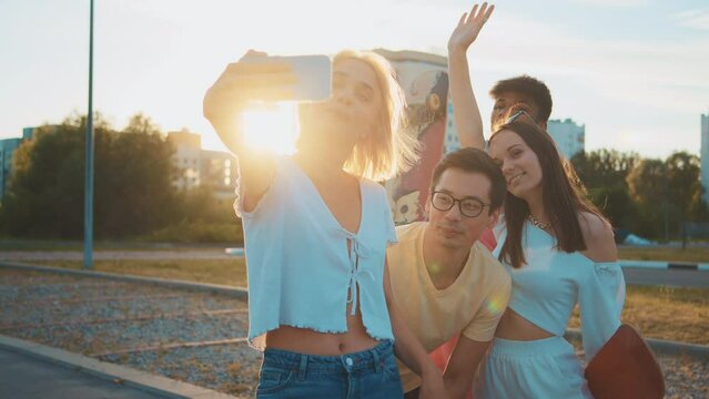 Young multi-ethnic hipster friends on summer holidays make selfie using smartphone at beach. Four young multiracial people spending time together. Friendship, communication, a youth lifestyle concept.