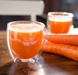 Organic carrot juice in glass on dark wooden background