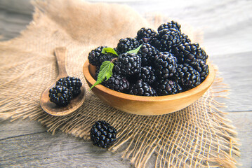 fresh blackberries in wooden bowl on gray table. Close-up, macro.