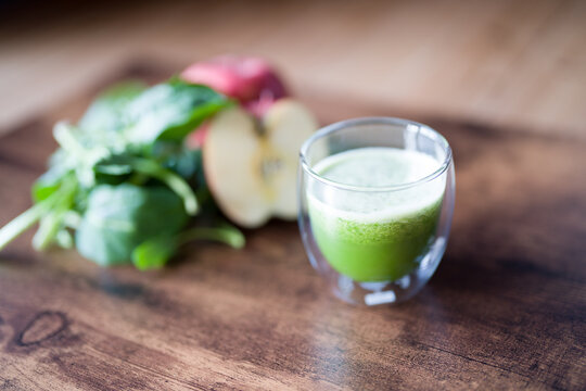 Organic spinach smoothie with spanich leaves and apple on dark wooden background. selective focus