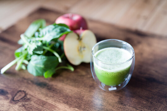Organic spinach smoothie with spanich leaves and apple on dark wooden background. selective focus