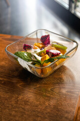 Various fresh mix salad leaves with mangoes, pitaya in glass bowl on wooden table