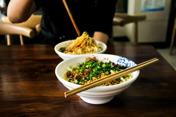 a chinese women is eating chinese style fried noodles
