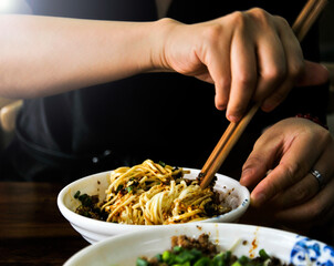 a chinese women is eating chinese style fried noodles