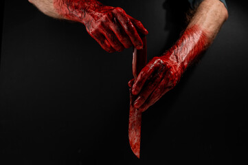 Fototapeta Man holding knife with bloody hand on black background.  obraz