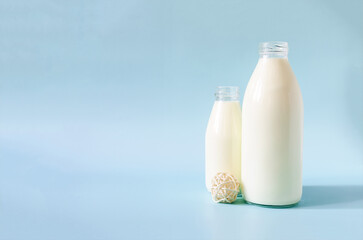 Milk in glass bottles with white decor on a blue background is a place for text.