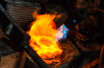 Close up of Jeweler crafting golden bracelet with flame torch
