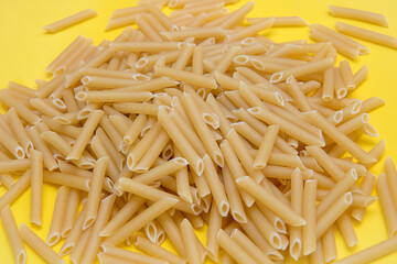 scattered pasta feathers on light yellow background