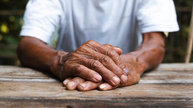 Close up of male wrinkled hands, old man is wearing on the wood table.