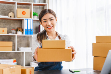 Looking camera, Start up successful small business owner, a freelance young Asian female merchant preparing a package box to deliver to customers, SME entrepreneurs.