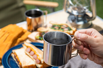 屋外キャンプでコーヒーを淹れて飲む男性の手元