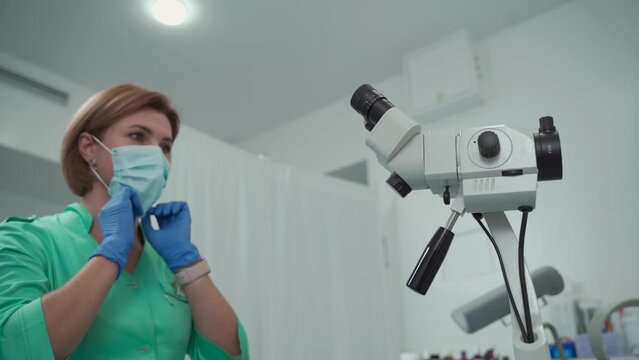 Medicine occupation career. A woman gynecologist puts on a protective mask and works with a colposcope in a modern women's health clinic. Gynecologist profession. Health feminine checkup.
