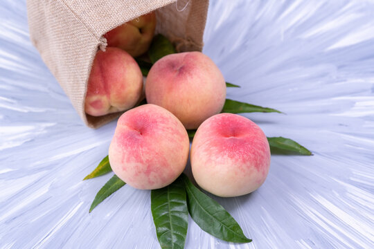Fresh Sweet Peach on blue wooden  background, Pink and yellow Peach fruit with leaf with natural color cloth bagt.