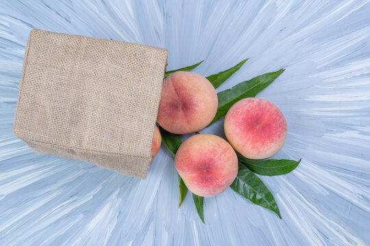 Fresh Sweet Peach on blue wooden  background, Pink and yellow Peach fruit with leaf with natural color cloth bagt.