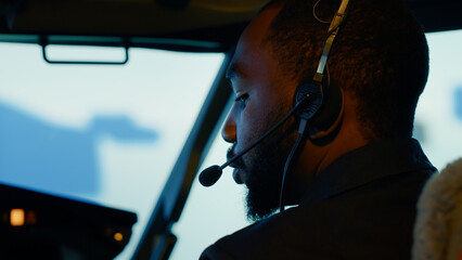 African american copilot preparing to takeoff and fly plane, using dashboard command in cockpit. Windscreen navigation and control panel buttons to travel with airplane. Close up.
