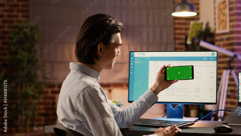 Poster businessman holding smartphone with horizontal greenscreen at desk. looking at isolated mockup backg