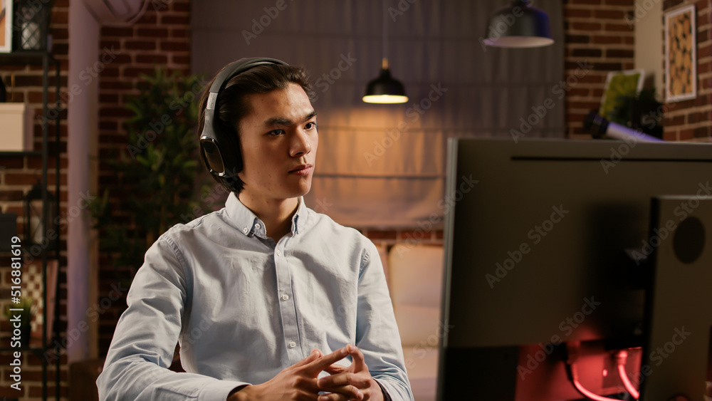 Poster company employee listening to podcast episode or webinar, using computer to do remote work for start