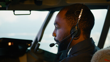 African american copilot taking off with airplane captain, using aircraft command on dashboard in...