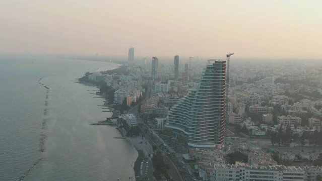beautiful drone shot of the cityscape and coastline of Limassol in Cyprus during sunset with many skyscrapers, buildings and the seafront