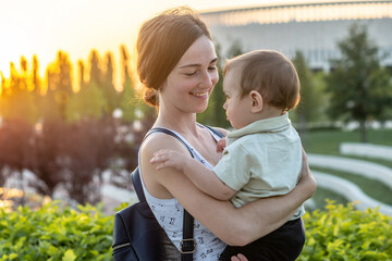 A young happy mother with a young son walks through the park on a summer day at sunset. Concept of...