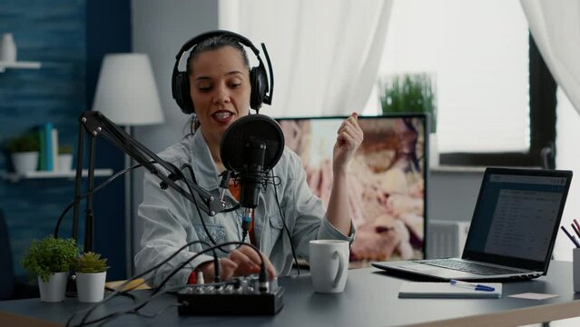 Famous social media influencer tweaking knobs on mixer while recording vlog for video sharing platforms. Popular internet star sitting at home studio desk while filming digital content.