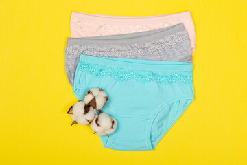 Clothing for children in the form of panties. Clothes for children from soft fabric. Panties for girls. A set of panties for children. View from above. Set of underwear on a yellow background