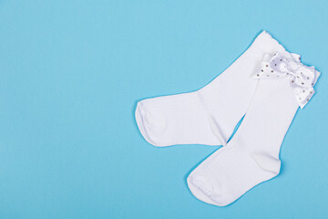 high white children's socks with big bows for festive clothes on a blue background top view