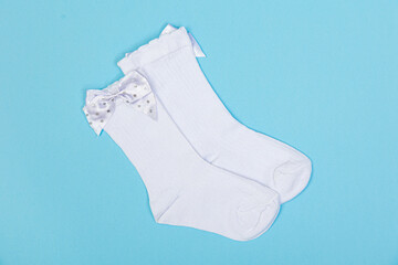 high white children's socks with big bows for festive clothes on a blue background top view
