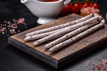 Delicious dry sausage with walnuts on a concrete table. Dry cured fuet sausage on a dark background