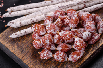 Delicious dry sausage with walnuts on a concrete table. Dry cured fuet sausage on a dark background