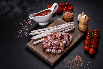 Delicious dry sausage with walnuts on a concrete table. Dry cured fuet sausage on a dark background