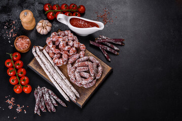 Delicious dry sausage with walnuts on a concrete table. Dry cured fuet sausage on a dark background