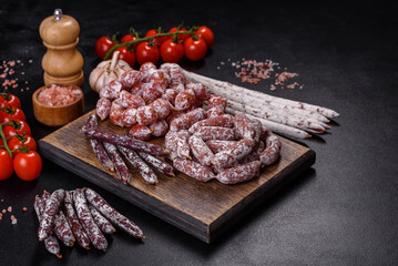 Delicious dry sausage with walnuts on a concrete table. Dry cured fuet sausage on a dark background