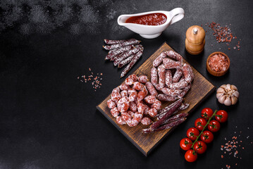 Delicious dry sausage with walnuts on a concrete table. Dry cured fuet sausage on a dark background