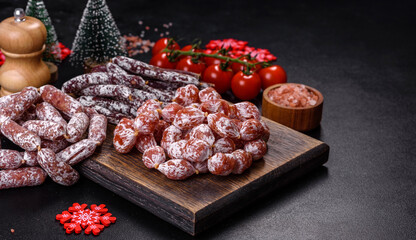 Delicious dry sausage with walnuts on a christmas table. Dry cured fuet sausage on a dark background
