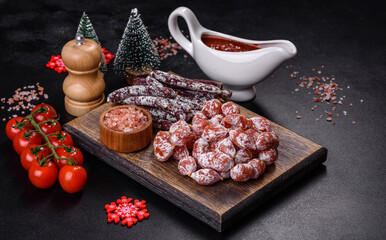 Delicious dry sausage with walnuts on a christmas table. Dry cured fuet sausage on a dark background