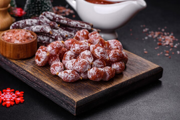 Delicious dry sausage with walnuts on a christmas table. Dry cured fuet sausage on a dark background
