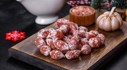 Delicious dry sausage with walnuts on a christmas table. Dry cured fuet sausage on a dark background