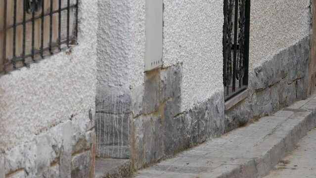 Handheld two cow, brown and black, running towards camera on street at traditional celebration, encierro, in Spain. Village one-storey town houses. Metal gate on doors, windows.