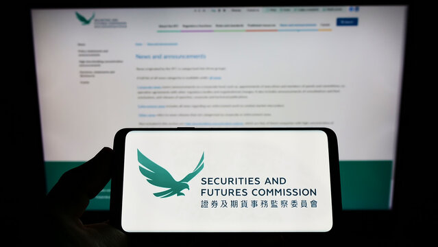 Stuttgart, Germany - 07-10-2022: Person holding smartphone with logo of Hong Kong Securities and Futures Commission (SFC) on screen in front of website. Focus on phone display.