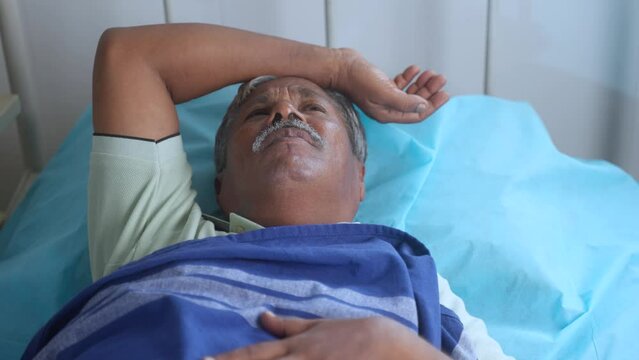 Elderly senior man suffering from insomnia while admitted to hospital - concept of mental illness, disease and loneliness.